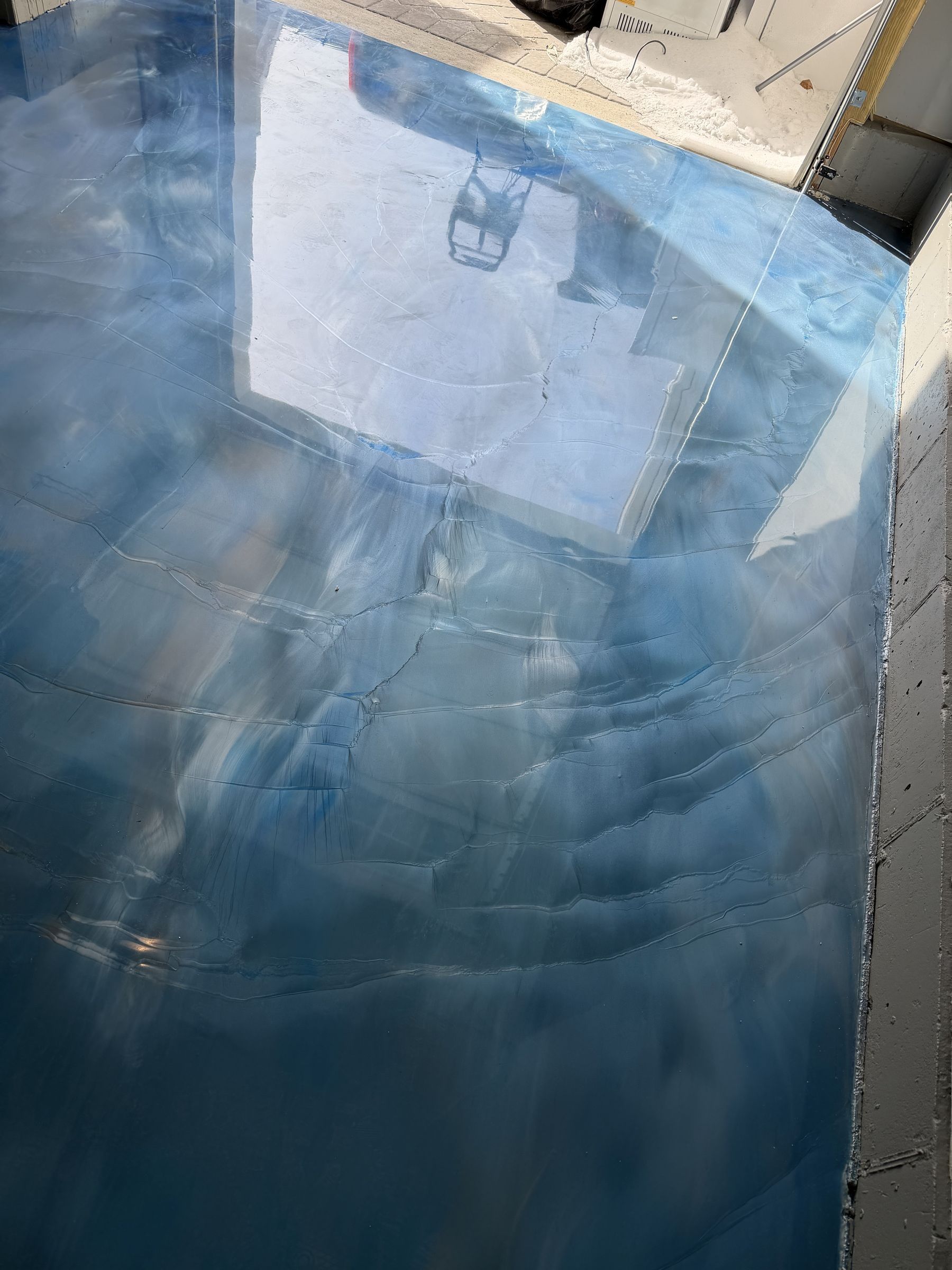 Glossy blue and white metallic epoxy floor reflecting the open garage door