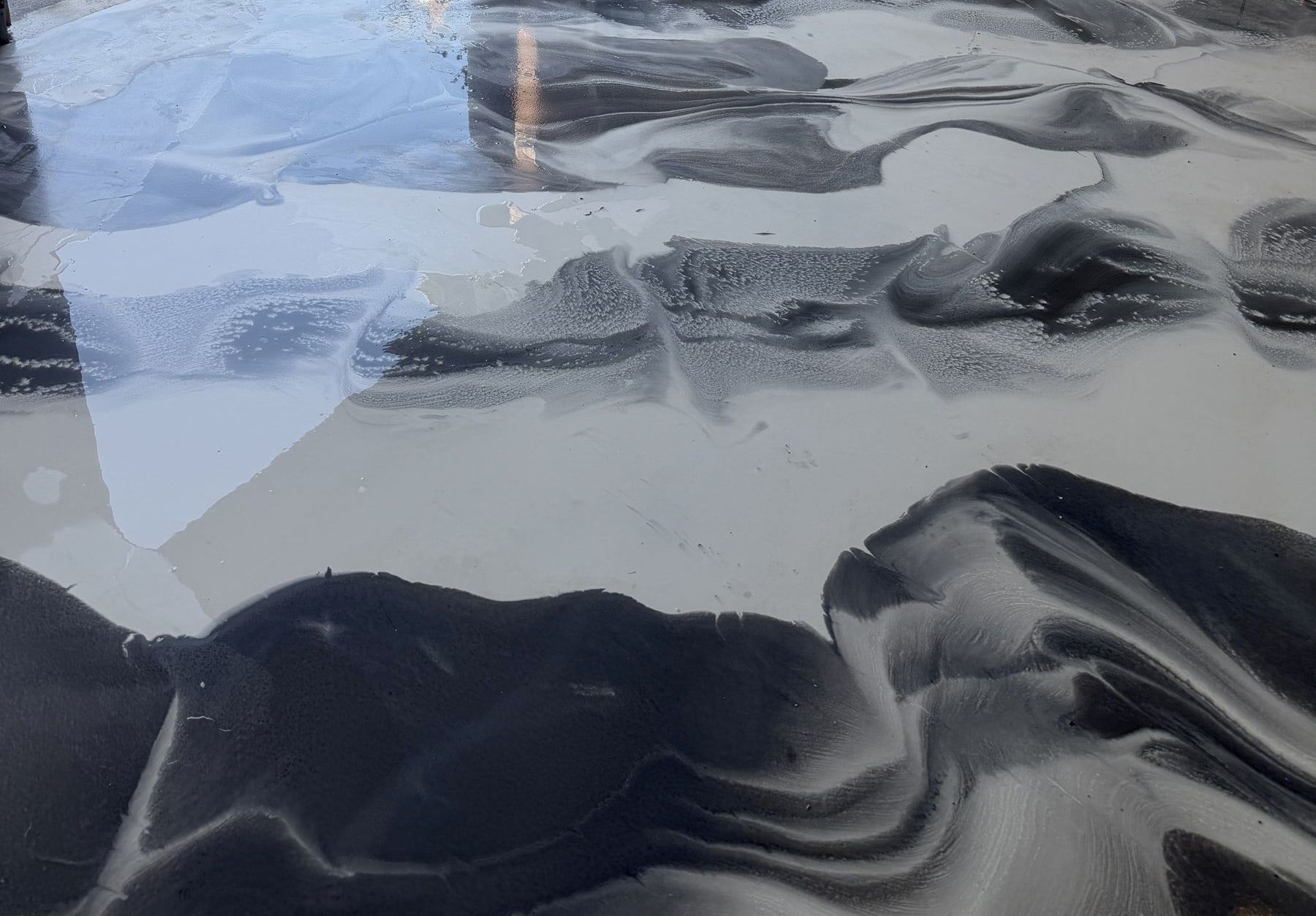 Garage with a white metallic epoxy floor with dark charcoal swirls, open to the driveway