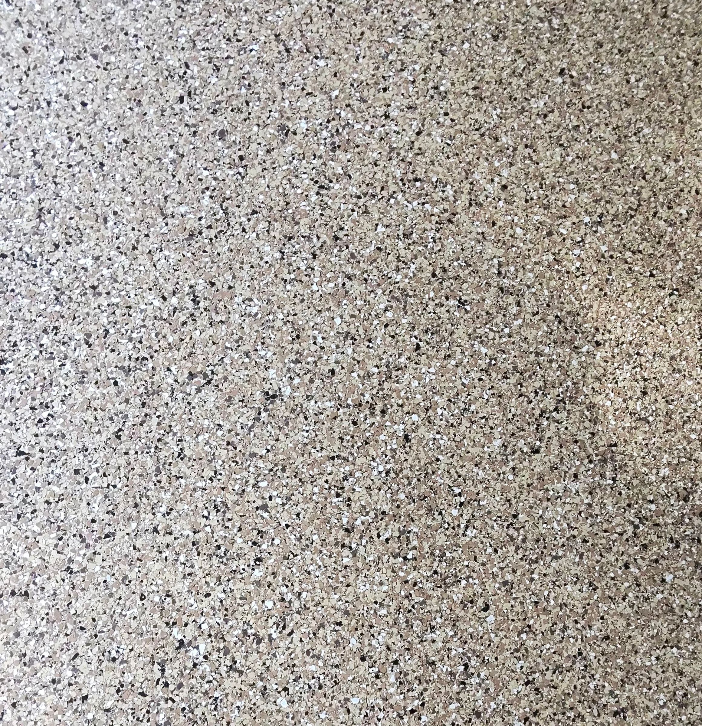 Close-up of tan, grey, black and white vinyl flake chips in an epoxy floor