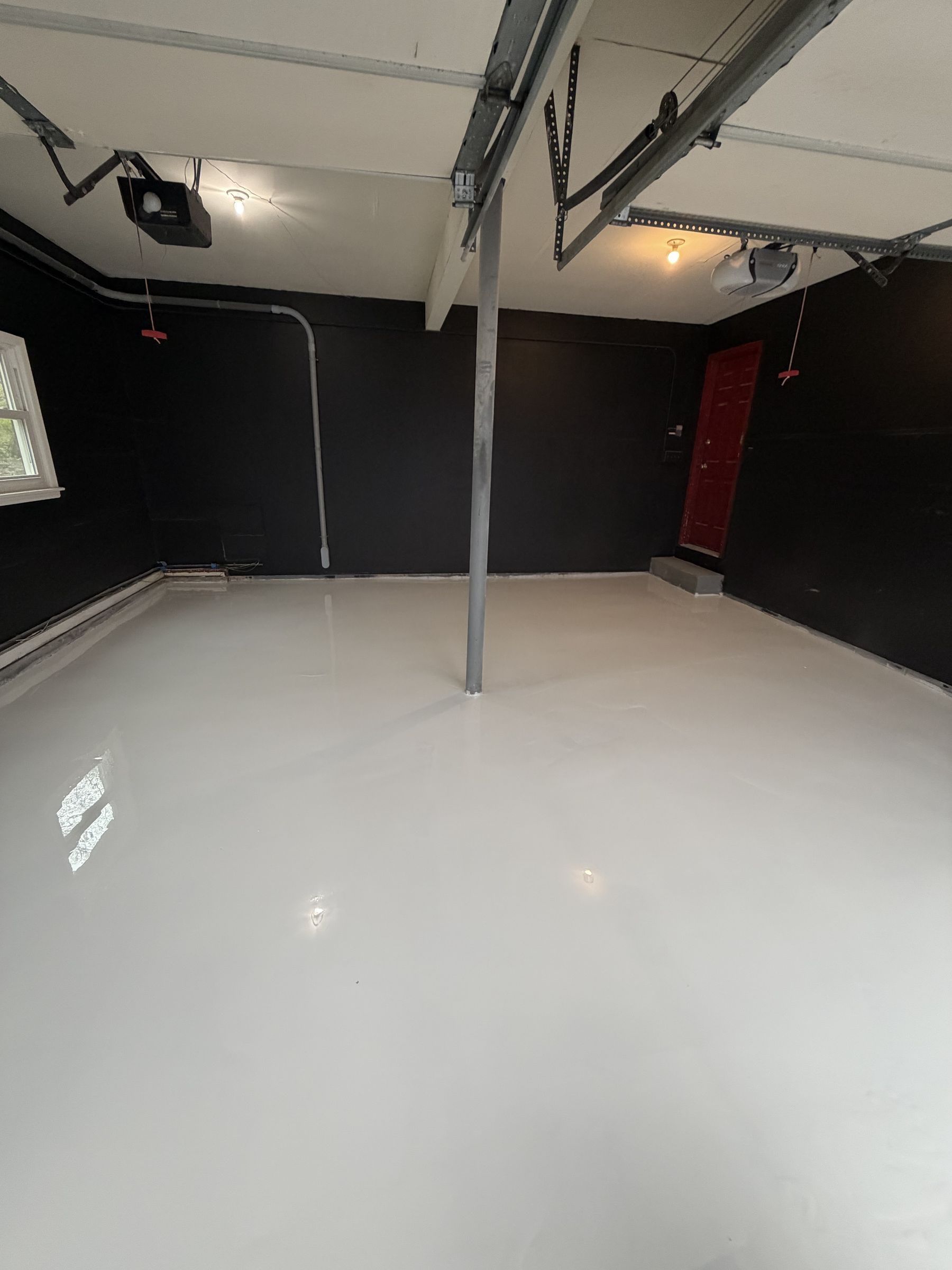 Glossy light grey metallic epoxy floor in a two-car garage with black walls