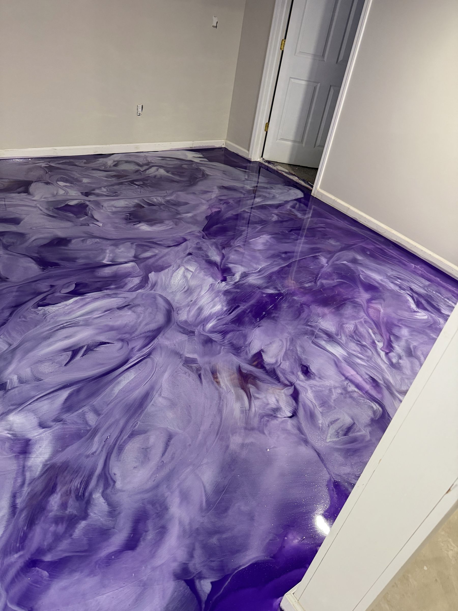 Basement room with a glossy purple and white swirled metallic epoxy floor