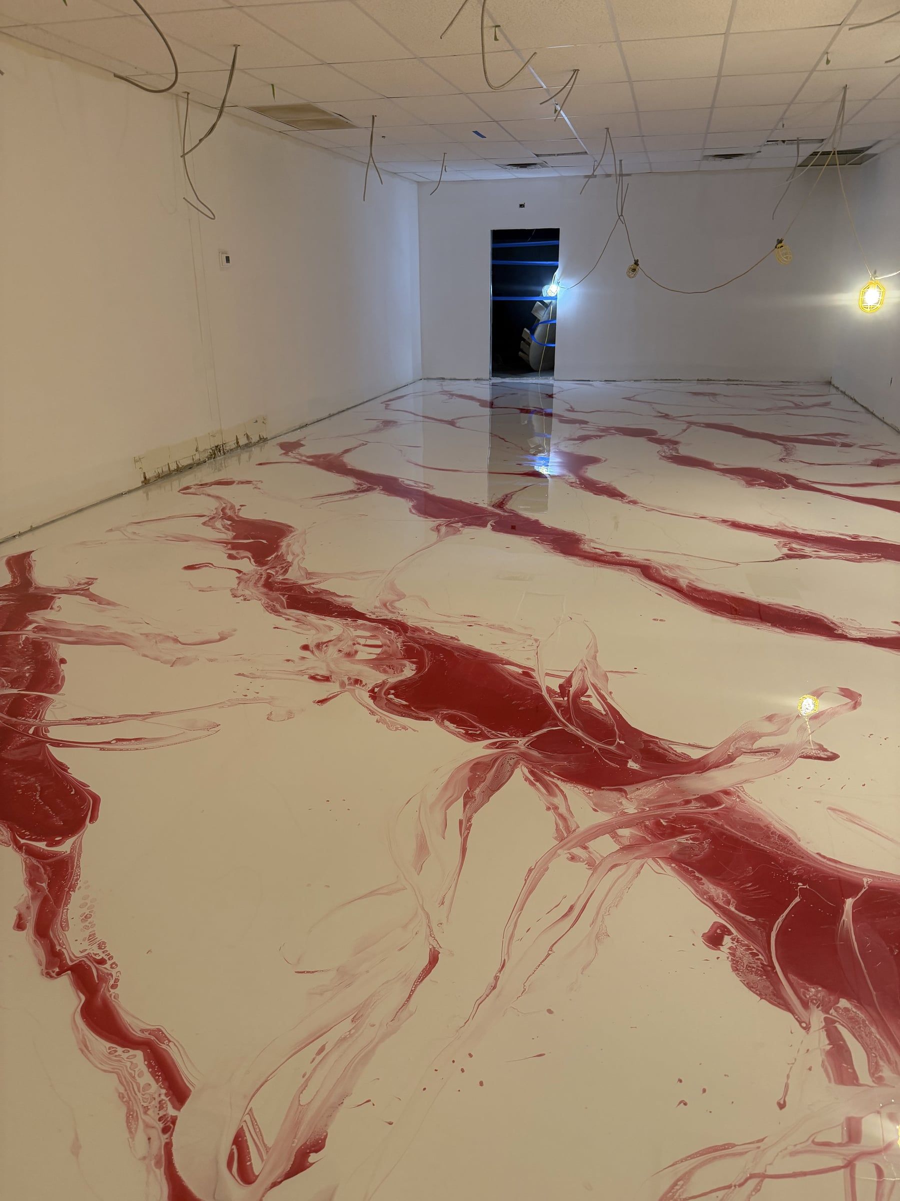 Long commercial space with a glossy white metallic epoxy floor veined in red