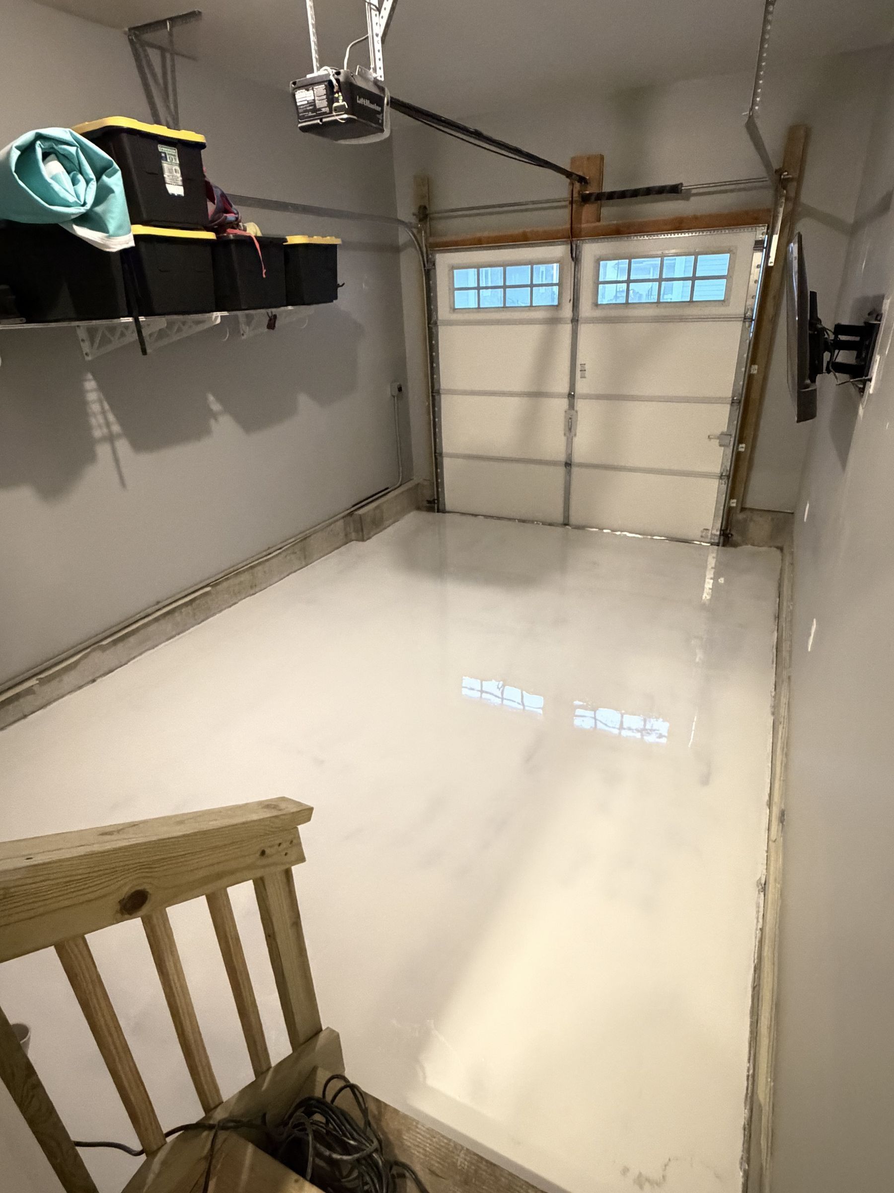 Finished glossy white metallic epoxy floor in a one-car garage
